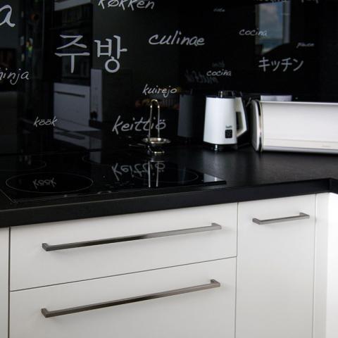 Kuchnia, lakierowane fronty kontrastują z czarnym szkłem na ścianie